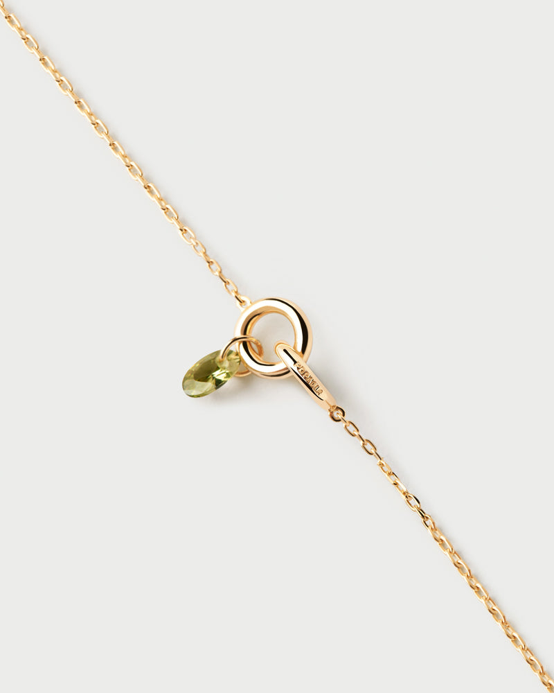 Gold-plated bracelet featuring two interlinked rings with a green zirconia drop pendant